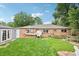 Spacious backyard with lush green grass, brick house, and a wooden fence at 9150 Fir Dr, Thornton, CO 80229