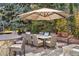 Spacious outdoor dining area with large umbrella, surrounded by trees and a decorative stone accent wall at 2 Fieldstone Trl, Englewood, CO 80113