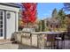 Stone outdoor kitchen with built-in grill, bar seating, and manicured garden, perfect for entertaining at 2 Fieldstone Trl, Englewood, CO 80113