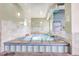 An indoor hot tub room with tiled walls, lights, and a hot tub with metal ladders for entry and exit at 13931 E Marina Dr # 402, Aurora, CO 80014