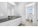 Modern bathroom featuring a sleek vanity with dark countertop and white cabinets, leading to a shower area at 864 Clover Loop, Erie, CO 80026