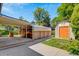 A large backyard with a covered patio area, a hot tub, and a metal storage shed with an orange door at 3055 S Winona Ct, Denver, CO 80236