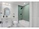 Contemporary bathroom with white vanity, oval mirror, toilet, and stylish green-tiled shower and tub featuring black fixtures at 3055 S Winona Ct, Denver, CO 80236