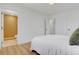 Bright bedroom with wood-look floors, a white bed, open bathroom door, and modern white doors creates a relaxing and inviting space at 3055 S Winona Ct, Denver, CO 80236