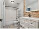 This renovated bathroom features stone accents, a white vanity, and a shower-tub combo at 3746 S Fairplay Way, Aurora, CO 80014