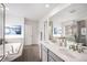 Sleek primary bathroom with a double vanity, soaking tub, and separate glass-enclosed shower at 16317 Saint Paul St, Thornton, CO 80602