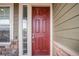 Close-up of a red front door with a sidelight, stone accents, and neutral siding at 16317 Saint Paul St, Thornton, CO 80602