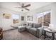 Comfortable living room with a gray sectional couch, ceiling fan, and multiple windows for natural light at 16317 Saint Paul St, Thornton, CO 80602