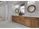 Bright bathroom featuring a double vanity with wooden cabinets, quartz countertop, and decorative framed mirrors at 11299 Star Streak Ln, Littleton, CO 80125