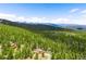 Panoramic aerial view showcases the home situated among tall trees and mountain ranges at 10090 Blue Sky Trl, Conifer, CO 80433