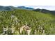 Aerial view of the home nestled in a lush forest setting with scenic mountain views in the background at 10090 Blue Sky Trl, Conifer, CO 80433