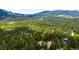 Expansive aerial shot of a home surrounded by dense forestry with stunning mountain range backdrop at 10090 Blue Sky Trl, Conifer, CO 80433