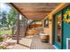 Inviting covered back porch with a wooden swing, barrel table, and stairs to the upper level at 10090 Blue Sky Trl, Conifer, CO 80433