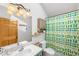 Well-lit bathroom featuring a tub with shower, unique cactus-themed shower curtain and single sink vanity at 10090 Blue Sky Trl, Conifer, CO 80433