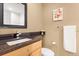 Stylish half bath featuring a granite countertop, wooden vanity, and decorative floral art at 12674 E Bates Cir, Aurora, CO 80014