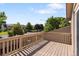 Outdoor deck with wood railings and a view of the front neighborhood street and lush trees at 12674 E Bates Cir, Aurora, CO 80014