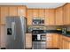 Close up of stainless steel appliances, wood cabinets, and granite countertops in the bright eat-in kitchen at 12674 E Bates Cir, Aurora, CO 80014