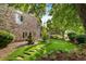 Side view of a brick home with a flagstone path, with manicured gardens and mature trees enhancing the landscape at 4532 Christensen Cir, Littleton, CO 80123