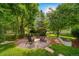 Serene backyard featuring mature trees and a cozy fire pit area with Adirondack chairs at 4532 Christensen Cir, Littleton, CO 80123