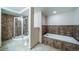 Spa-like bathroom featuring a glass-enclosed shower and a soaking tub with tile surround at 4532 Christensen Cir, Littleton, CO 80123