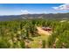 Breathtaking aerial view of a country property with a well-maintained house, barns, and lush surrounding landscape at 8838 Hillview Rd, Morrison, CO 80465
