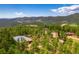 Spacious aerial view of mountain property with barns, outbuildings, lush trees, and mountain views at 8838 Hillview Rd, Morrison, CO 80465