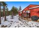 The backyard of this red house features a deck, outdoor seating, and snowy surroundings at 8838 Hillview Rd, Morrison, CO 80465