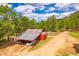 Aerial view of charming red house with a covered parking area, surrounded by lush green trees at 8838 Hillview Rd, Morrison, CO 80465