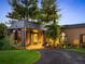 A long curved driveway approaches the front entrance of the home, lushly landscaped with mature trees and flower beds at 9 Sedgwick Dr, Englewood, CO 80113