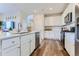 A kitchen with white cabinetry, stainless steel appliances, an island with a sink, and wood floors at 14151 Deertrack Ln, Parker, CO 80134