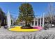 A town center shows a plaza with a tree in the middle and colorful seating areas, surrounded by retail shops at 451 S Reed St, Lakewood, CO 80226
