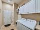 Functional laundry room with white washer and dryer, tiled flooring, and overhead cabinets at 4420 White Rock Dr, Broomfield, CO 80023