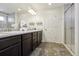 Bathroom featuring double vanity with dark wood cabinets, framed mirror, granite counters and grey wood-look tile floors at 18079 E 108Th Pl, Commerce City, CO 80022