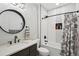 Modern bathroom with a sleek vanity, circular mirror, and black and white tile accents in the shower area at 18079 E 108Th Pl, Commerce City, CO 80022