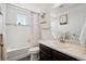 Bright bathroom featuring a tub with a patterned curtain, white tiling, and a sleek vanity with a marble countertop at 18079 E 108Th Pl, Commerce City, CO 80022