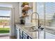 Modern kitchen with granite counters, stainless sink, floating shelves, and a view of the backyard at 18079 E 108Th Pl, Commerce City, CO 80022