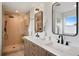 Stylish bathroom boasting a glass-enclosed shower with bench and a double sink vanity with black hardware at 2450 S Cherokee St, Denver, CO 80223