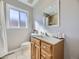 Bathroom featuring wood cabinets, neutral gray walls, white tile floors and modern mirror at 3361 W Saratoga Ave, Englewood, CO 80110