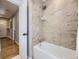 Bathroom displaying a white tub, and an open door showing wood floors at 3361 W Saratoga Ave, Englewood, CO 80110