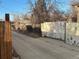 A shot of a long driveway with a peeling white wooden fence on one side and a brown one on the other at 1120 Dayton St, Aurora, CO 80010