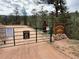 Community entrance gate featuring signage, stone accents, and serene forest backdrop at 9716 Canon Dr, Sedalia, CO 80135