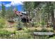 Stunning multi-story home with stone accents and a red metal roof surrounded by lush green trees and a tranquil pond at 9716 Canon Dr, Sedalia, CO 80135