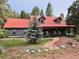 Charming cabin featuring a red metal roof, inviting front porch with rocking chairs, and a stone pathway at 9716 Canon Dr, Sedalia, CO 80135