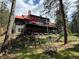 Spacious mountain home with a stone foundation, red roof, and multiple decks, surrounded by towering trees at 9716 Canon Dr, Sedalia, CO 80135