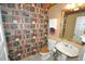 A powder room featuring unique book-themed wallpaper, wood toilet seat, and a pedestal sink at 9716 Canon Dr, Sedalia, CO 80135