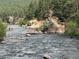 Scenic river view with rock formations, lush trees, and a person fly-fishing in the distance at 9716 Canon Dr, Sedalia, CO 80135