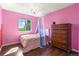 Bright pink bedroom featuring a chandelier, hardwood floors, and backyard views at 5249 Mt Arapaho Cir, Frederick, CO 80504