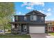 Two-story home boasts a welcoming porch with hanging flower baskets and a lush green lawn at 5249 Mt Arapaho Cir, Frederick, CO 80504