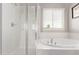 Bright bathroom featuring shower, soaking tub, tiled walls, and window with blinds at 6990 E 132Nd Pl, Thornton, CO 80602