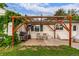 Backyard patio with a wooden pergola, string lights, BBQ grill, table, and manicured lawn at 3865 Independence Ct, Wheat Ridge, CO 80033